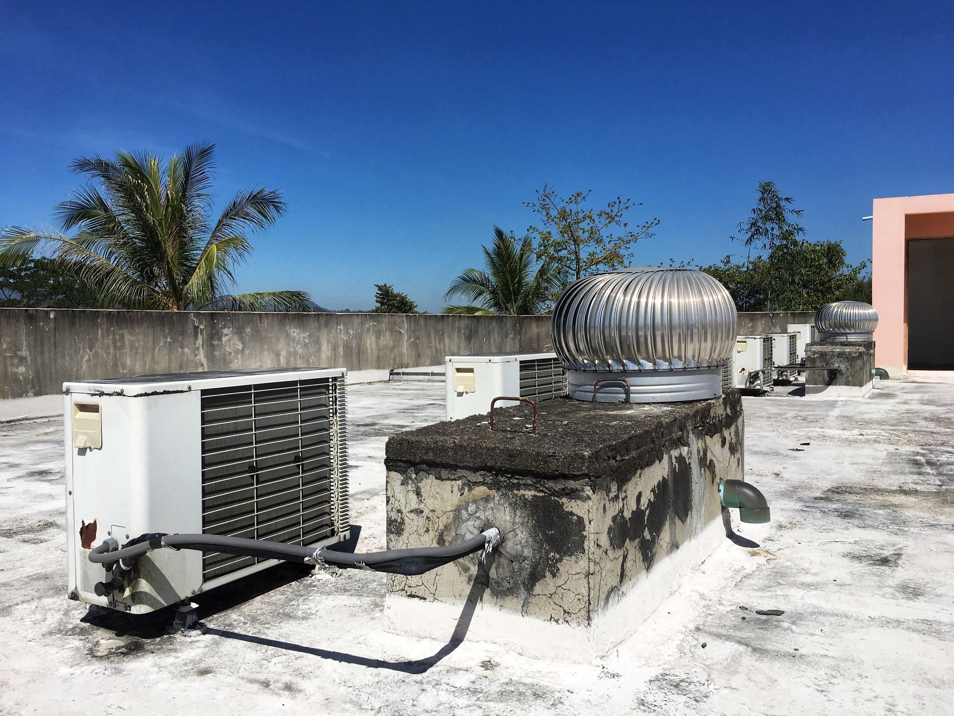 Air compressors on roof of hotel with blue sky background.